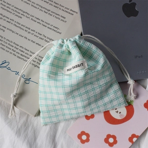 Detail of mint green checkered drawstring storage pouch with a stitched woven label