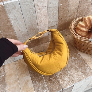 Detail of yellow quilted dumpling bag featuring water-resistant fabric and adjustable strap