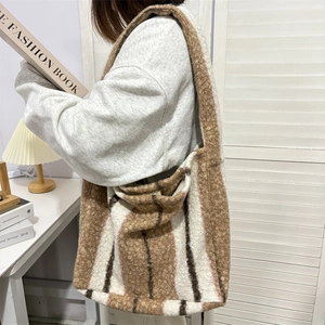 Fuzzy striped plush tote bag shown on model with warm winter aesthetic and large capacity