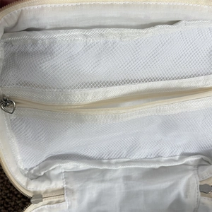 Détail des compartiments en filet et des fermetures éclair en cœur de la trousse de maquillage