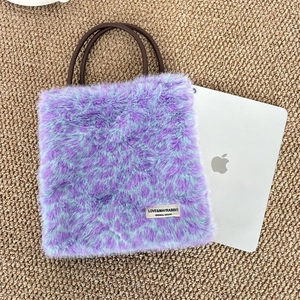Macro view of purple and blue faux fur handbag showing texture beside a tablet
