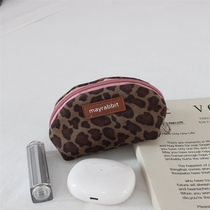 Detailed close-up of a leopard print coin purse with pink zipper and lifestyle accessories