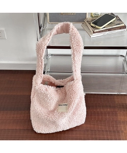 Detailed shot of pink plush shoulder bag with SEEYOU label on a wooden floor