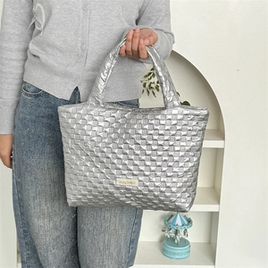 Detail view of metallic silver woven tote bag with quilted puffy squares and woven label