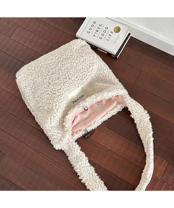 Detail of plush off-white sherpa tote bag featuring pink lining and cartoon illustration
