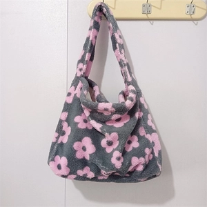 Detail of plush tote bag with grey base and pink flower pattern hanging on wall