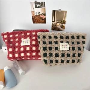 Detail of plush checkered vanity bags with embroidered label and soft lamb wool texture