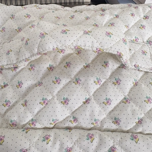 Détail d'une trousse de maquillage matelassée avec motif floral et coutures en losange