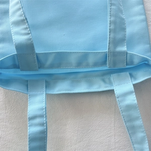 Close-up of sky blue canvas bag showing reinforced stitching and handle attachment