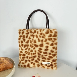 Detail of plush leopard print handbag showing a round handle and brand label on faux fur