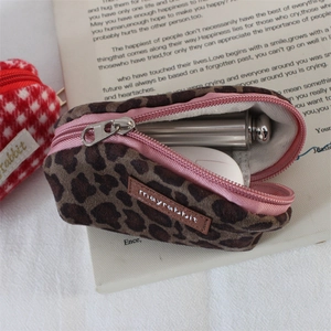 Detailed view of leopard print suede pouch storing lipstick and earphones for daily use