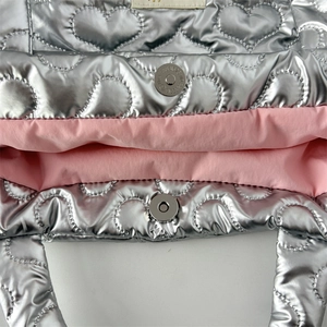 Detail of silver heart quilted bag showing pink lining and magnetic metal closure