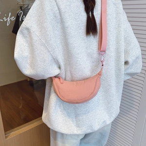 Detail of pink crescent bag with adjustable wide strap and resin hook in a lifestyle setting