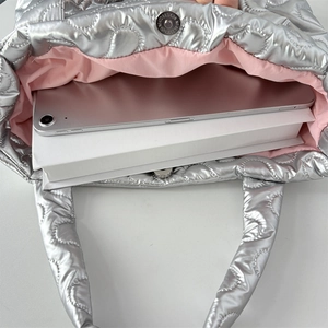 Top view of silver quilted heart handbag showing interior space with tablet and pink lining