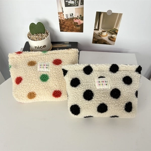 Macro shot of fluffy polka dot plush cosmetic bag with sheep wool texture and brand label