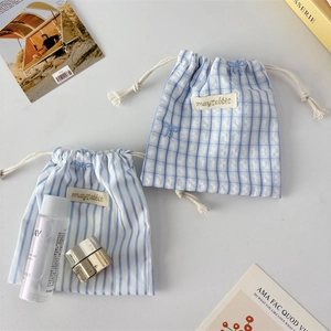 Striped fabric drawstring storage bag with ribbon bow and embroidered rabbit tag