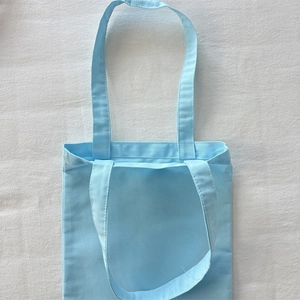 Detailed close-up of light blue thick canvas tote bag laid flat on textured fabric