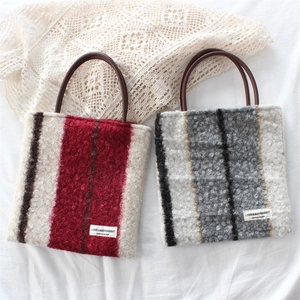 Detail of striped plush tote bags with faux fur texture and leather handles on white fabric