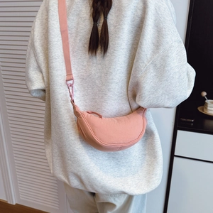 Rear view of model wearing a pink nylon crescent crossbody bag with adjustable wide strap