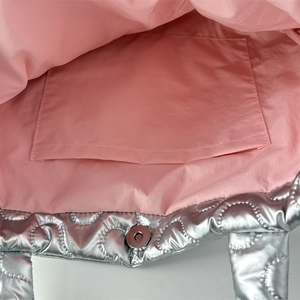 Detail of silver quilted handbag showing pink fabric lining and magnetic snap closure