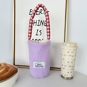 Detail of purple plush water bottle sleeve with red checkered handle and cartoon label
