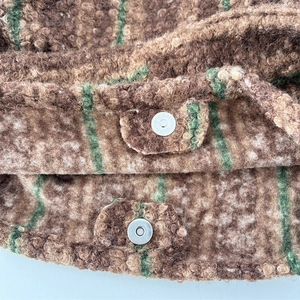 Macro detail of striped faux fur texture and silver metal snap buttons on tote bag