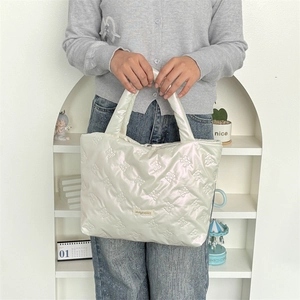 Detail of white quilted handbag featuring 3D bow patterns and pearlescent PU material