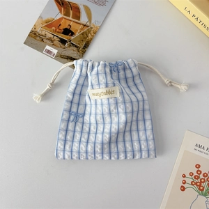 Detail showing blue and white checkered drawstring bag with bow embroidery and logo patch