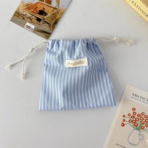 Close-up of blue striped drawstring pouch with cute rabbit embroidery and fabric texture