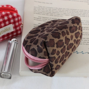 Leopard print faux suede shell coin purse with pink zipper on decorative book