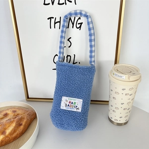 Detail of blue plush fleece bottle carrier with checkered handle and decorative tag