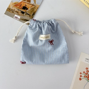 Detail of blue striped drawstring storage bag with red embroidered bow and cotton rope
