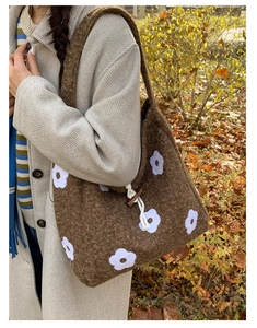 Detail of plush brown tote bag featuring white floral embroidery and wooden horn button