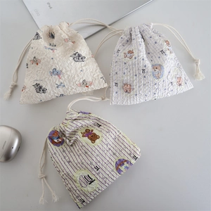 Textured cotton drawstring storage bags with cartoon prints in a cozy home office setting