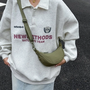 Outdoor shot of olive green nylon crescent crossbody bag with adjustable fabric strap