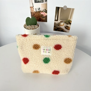 Detailed macro view of soft plush checkerboard makeup bag with colorful polka dots