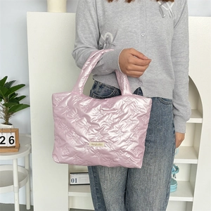 Close-up of pink puffy tote bag with bow-embossed texture and woven logo label