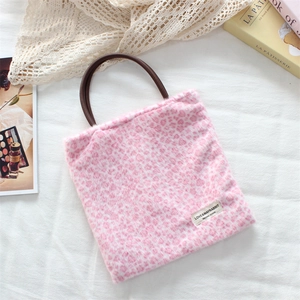 Detail of pink leopard faux fur tote bag with brown handles and brand label on white cloth