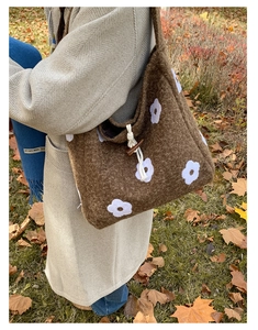 Detail of plush brown tote bag featuring daisy embroidery and wooden toggle button closure