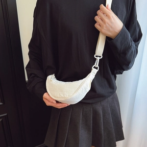 Detailed close-up of textured off-white crescent crossbody bag with wide nylon strap