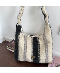 Dettaglio della borsa tote in peluche a righe verticali con tracolla arricciata e logo