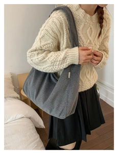 Detail of wool shoulder bag featuring a white textile label and soft fabric texture