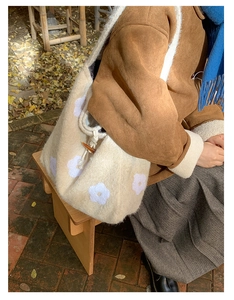 Detail of plush beige tote bag with white flower embroidery and dark toggle closure
