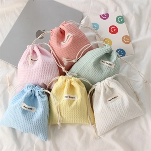 Flat lay of six colorful waffle texture drawstring bags with branded labels on white linen