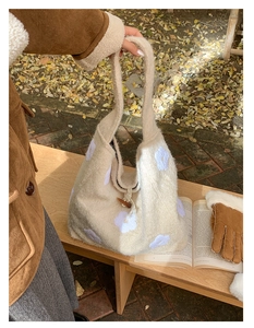 Detail of plush cream tote bag featuring white floral embroidery and wooden toggle closure