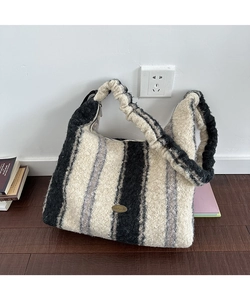 Dettaglio della borsa tote in peluche a righe con etichetta in metallo e cerniera