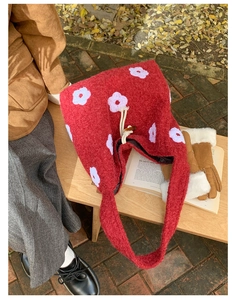 Detail of red plush tote bag with white floral embroidery and toggle drawstring closure