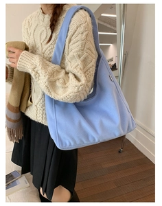 Close-up of soft light blue woolen tote bag with metal nameplate and wide shoulder strap