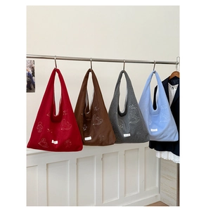 Detail of artistic bird embroidery on knitted tote bags in four versatile colors