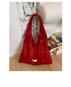 Detailed embroidery of birds and houses on a dark red felt tote bag placed on floor